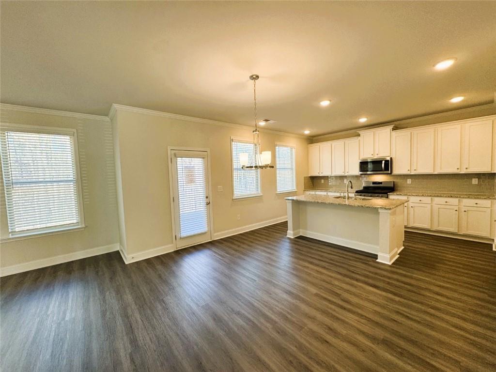 2180 Highridge Point Drive Lithia Springs, GA 30122 - Photo 9 of 24 a kitchen with granite countertop wooden floors stainless steel appliances and white cabinets