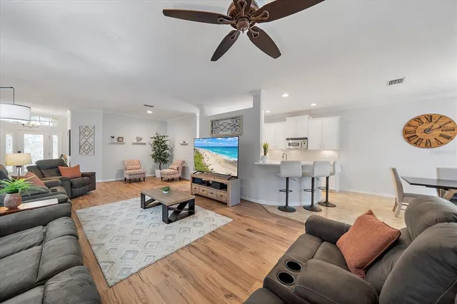 a living room with furniture kitchen view and a wooden floor