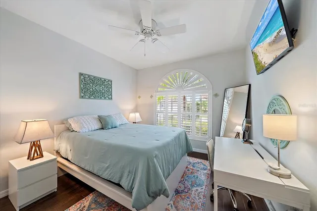 a spacious bedroom with a bed a chandelier and a flat tv screen on dresser