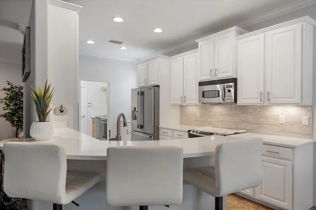 a kitchen with kitchen island white cabinets and stainless steel appliances