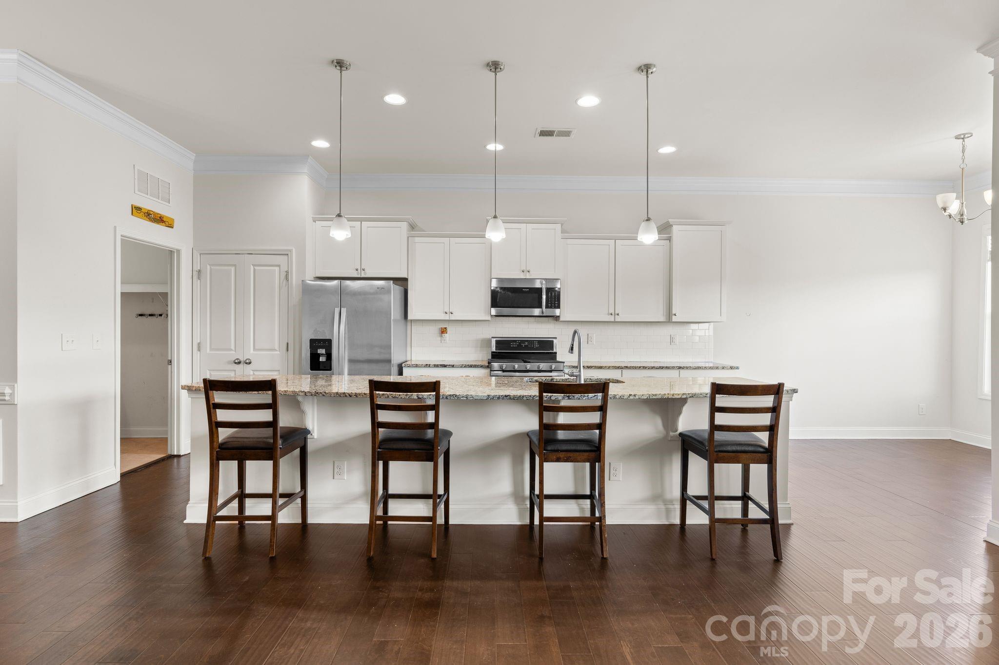 34 Rose Creek Road Leicester, NC 28748 - Photo 7 of 37 a kitchen with stainless steel appliances kitchen island granite countertop a dining table chairs and white cabinets