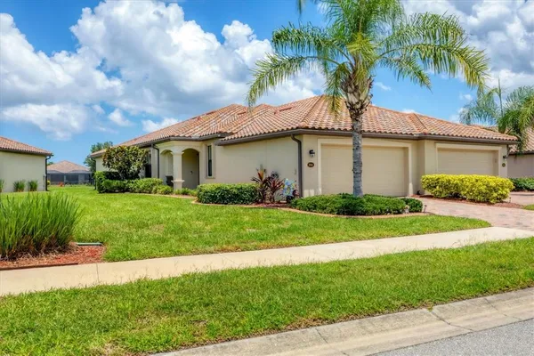 a white house with a small yard and palm trees