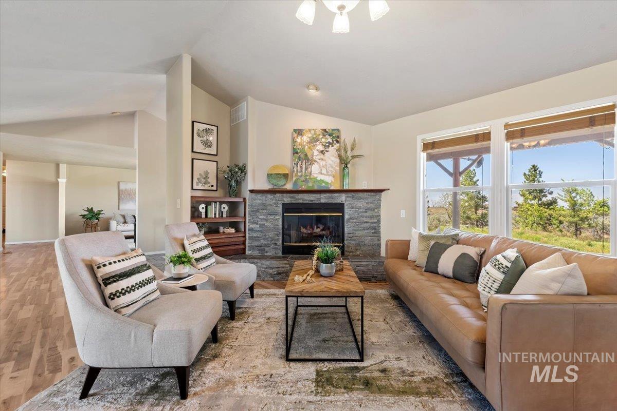 147 East Indian Crk Road Boise, ID 83716 - Photo 10 of 43 Living area featuring a stacked stone fireplace with a wood mantle, wood-finish flooring, and expansive windows