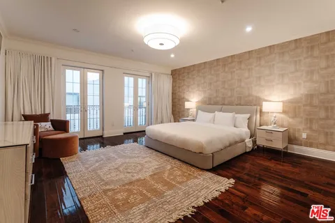 a bedroom with a large bed and wooden floor
