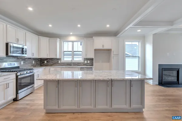 a large kitchen with granite countertop a stove top oven a sink a counter space and cabinets