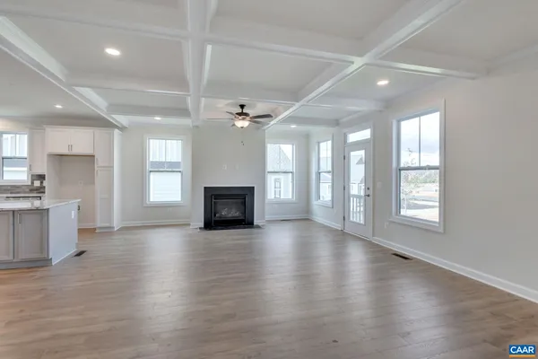 an empty room with wooden floor fireplace and windows
