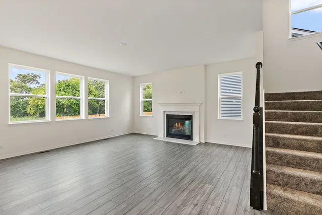 an empty room with wooden floor fireplace and windows