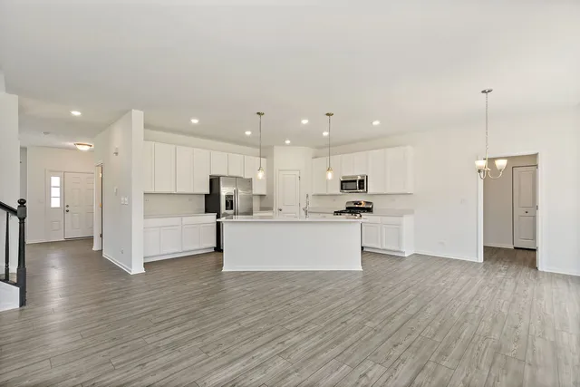 a view of kitchen with kitchen island stainless steel appliances refrigerator and stove top oven