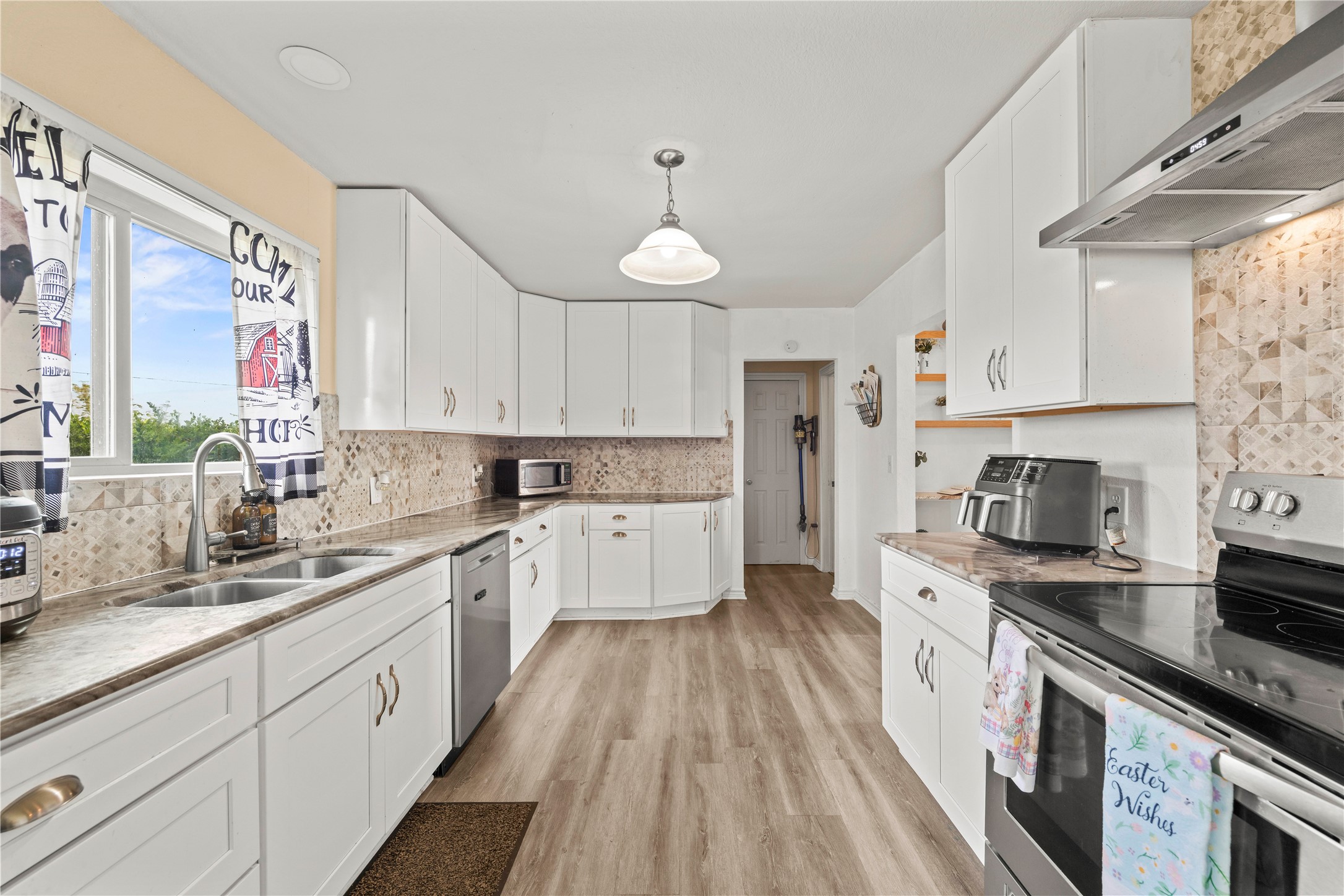 2915 County Road 153 Georgetown, TX 78626 - Photo 7 of 24 a large kitchen with stainless steel appliances granite countertop a stove a sink dishwasher and white cabinets with wooden floor