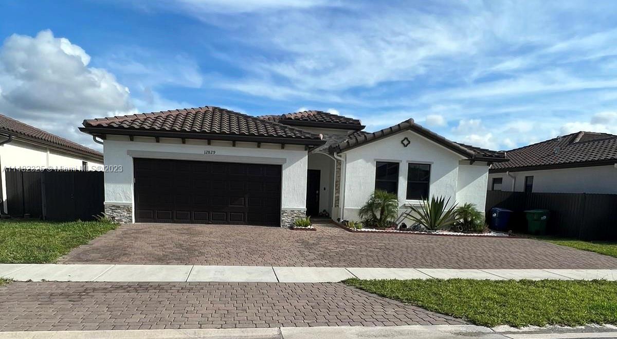 12829 Southwest 228th Street, Unit 2 Miami, FL 33170 - Photo 1 of 23 a front view of a house with a yard and garage