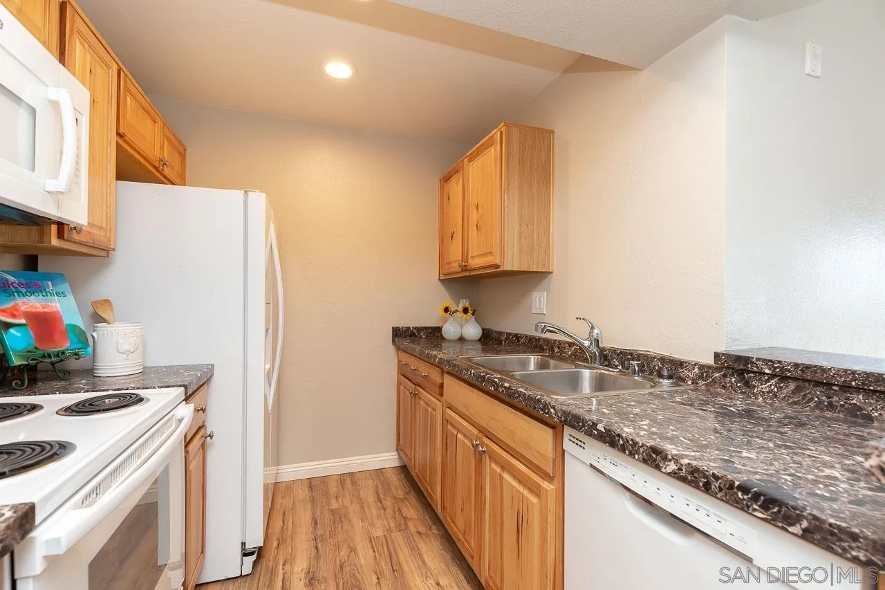6171 Rancho Mission Road, Unit 208 San Diego, CA 92108 - Photo 6 of 18 a kitchen with granite countertop a sink a stove and refrigerator
