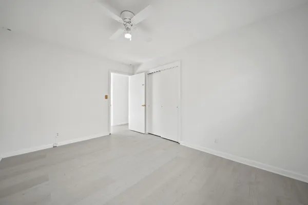 an empty room with windows and fan