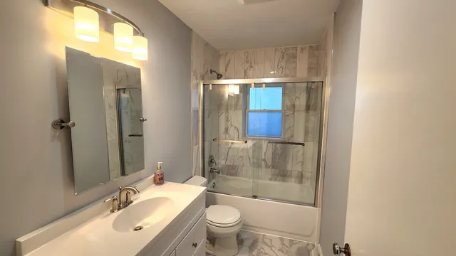a bathroom with a granite countertop sink toilet and shower