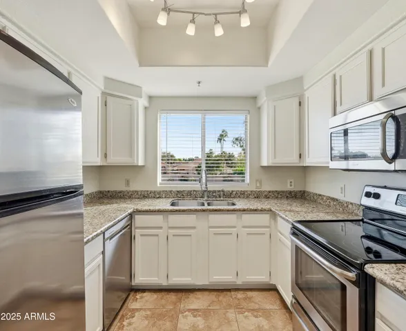 a kitchen with granite countertop a sink stainless steel appliances and cabinets
