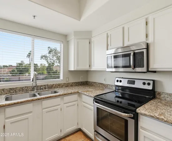 a kitchen with stainless steel appliances granite countertop white cabinets and a stove top oven
