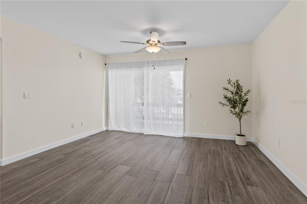 3405 Clark Road, Unit 205 Sarasota, FL 34231 - Photo 4 of 28 an empty room with wooden floor chandelier fan and windows