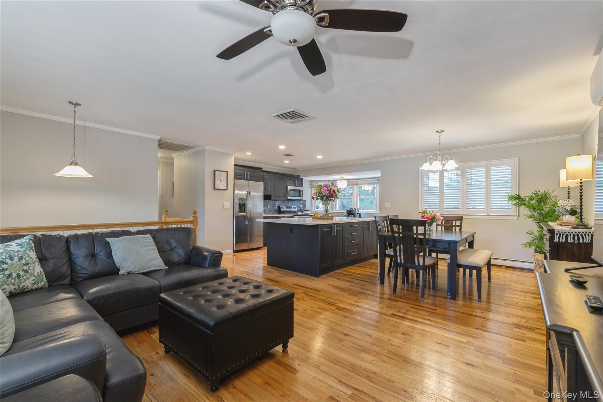 115 Clarendon Road Ronkonkoma, NY 11779 - Photo 7 of 45 Open-concept living space featuring wood-finish flooring, a ceiling fan with light fixture, and a kitchen island with seating