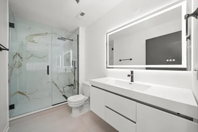 a bathroom with a sink a toilet and a large mirror