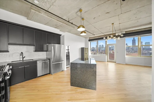 a large kitchen with kitchen island a large counter top space a sink stainless steel appliances and cabinets