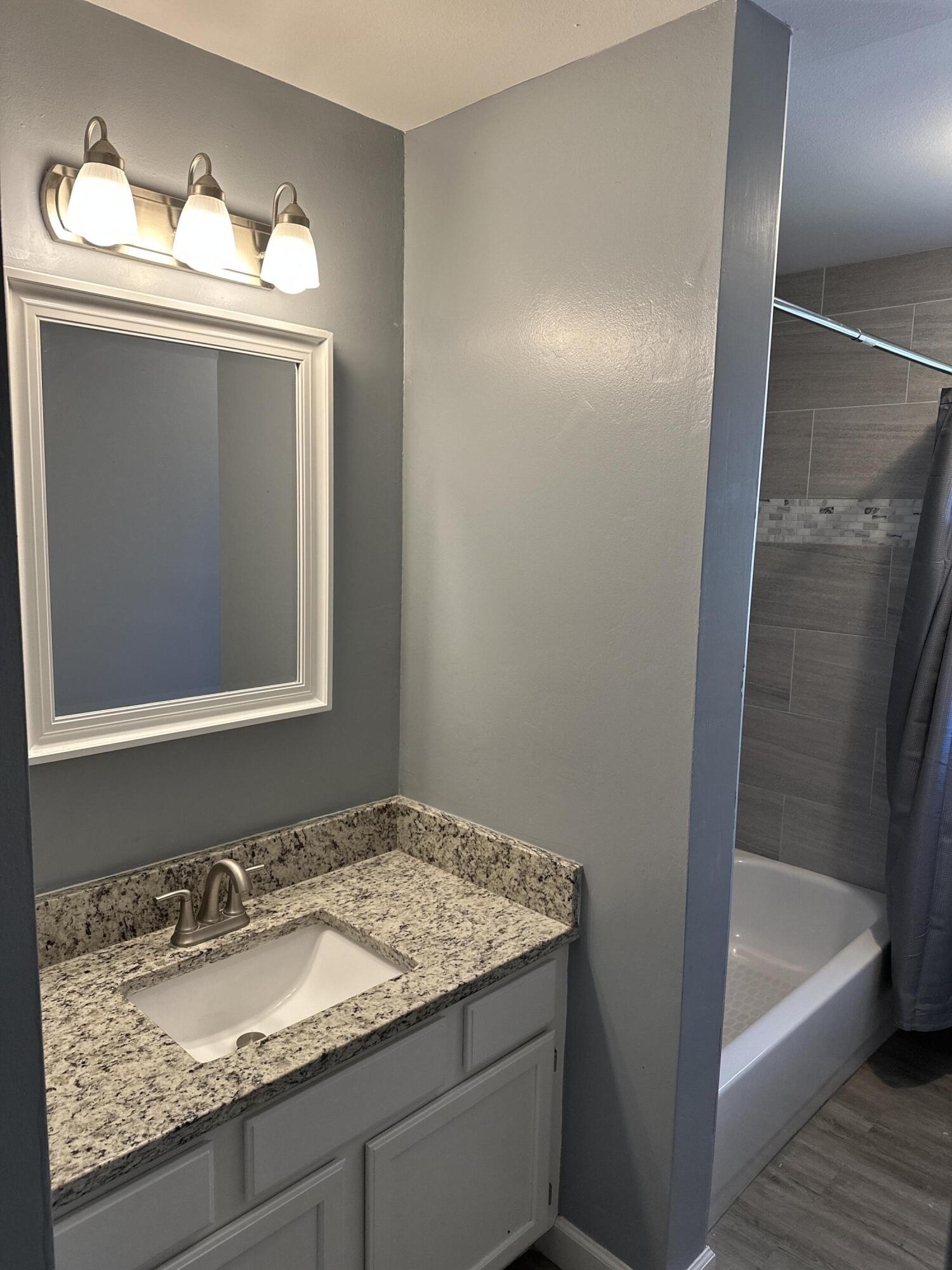 114 Wright Circle Niceville, FL 32578 - Photo 11 of 17 a bathroom with a granite countertop sink and mirror with bathtub