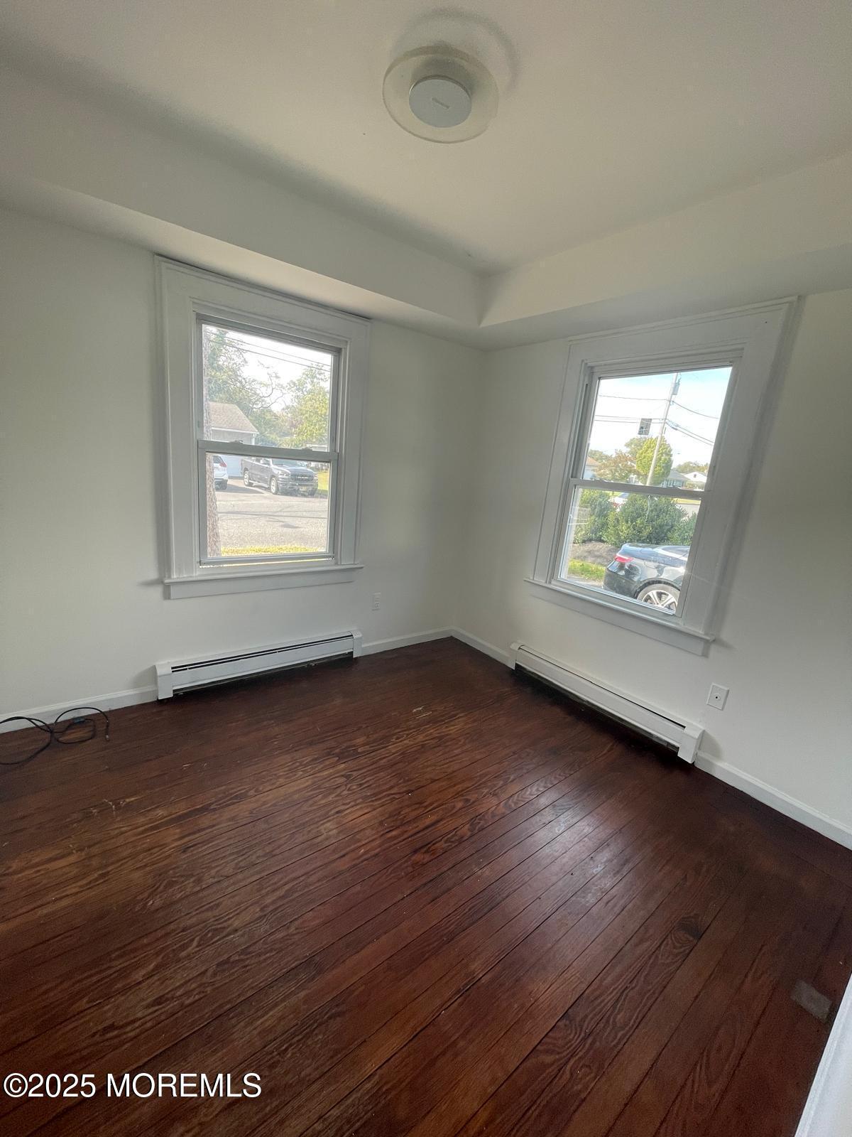 399 Park Avenue, Unit 1 Oakhurst, NJ 07755 - Photo 5 of 12 an empty room with wooden floor and windows