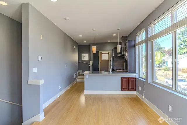a view of an empty room with a window and wooden floor