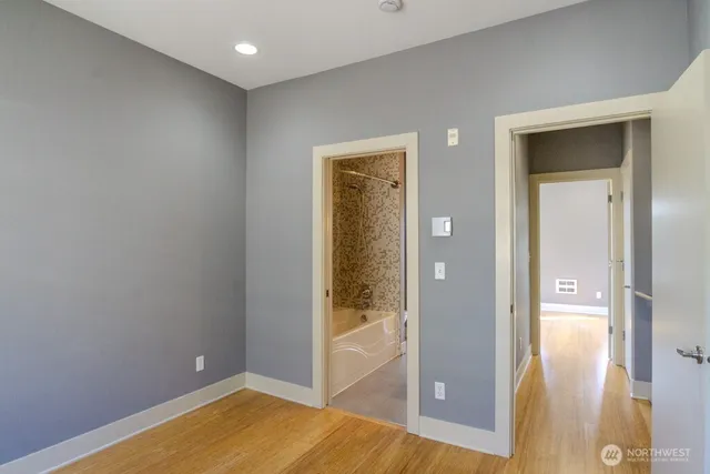 a view of a hallway with wooden floor a bathroom and a sink