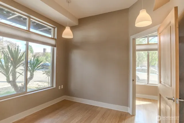 a view of an empty room with wooden floor and windows