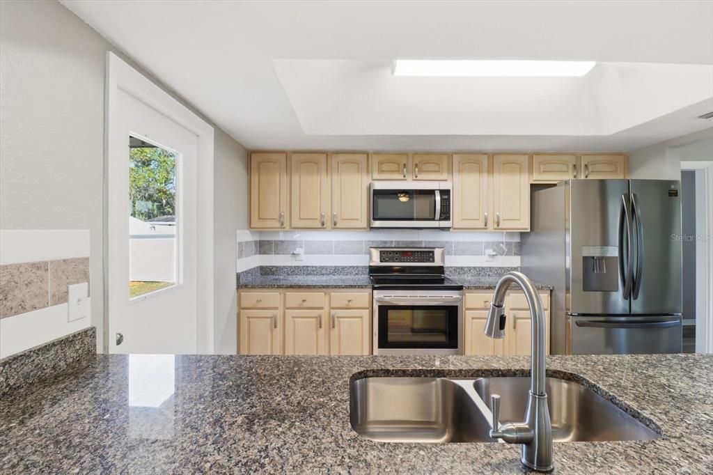 10256 East Pike Drive Inverness, FL 34450 - Photo 23 of 37 a kitchen with a sink a microwave a refrigerator and cabinets