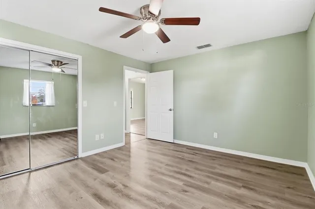 an empty room with wooden floor a ceiling fan and windows
