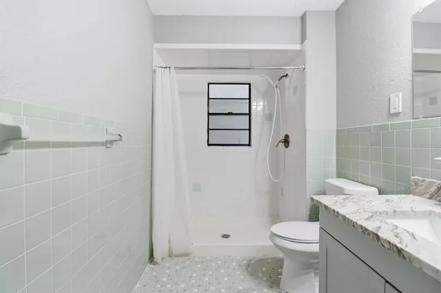a bathroom with a granite countertop sink a toilet and shower