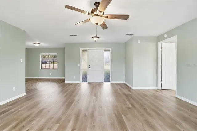 a view of an empty room with a window and wooden floor