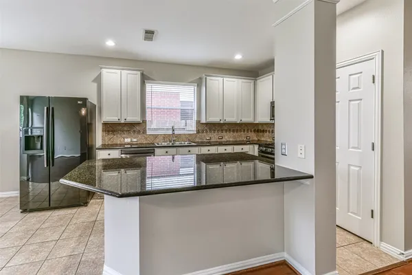 a kitchen with stainless steel appliances granite countertop a refrigerator a stove and a sink