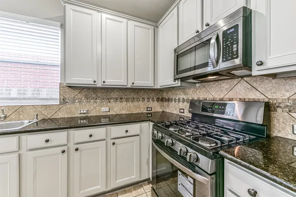 a kitchen with granite countertop a stove top oven microwave and cabinets