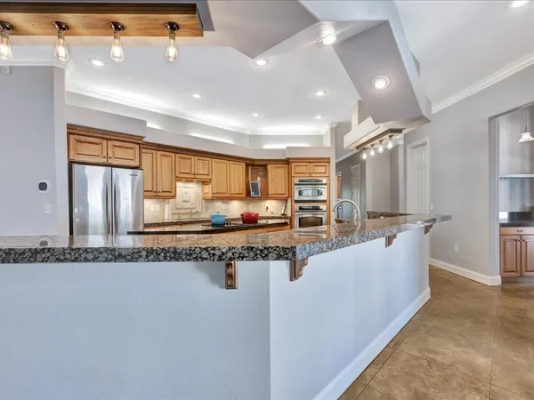a large kitchen with kitchen island a large counter top and stainless steel appliances