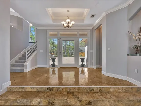 a view of an entryway with floor to ceiling windows and a chandelier