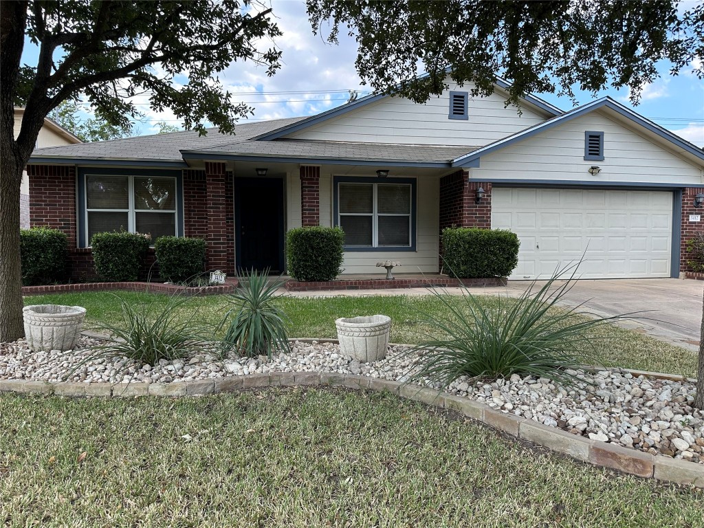 Ranch-style home with a porch, brick siding, a garage, driveway, and a front yard