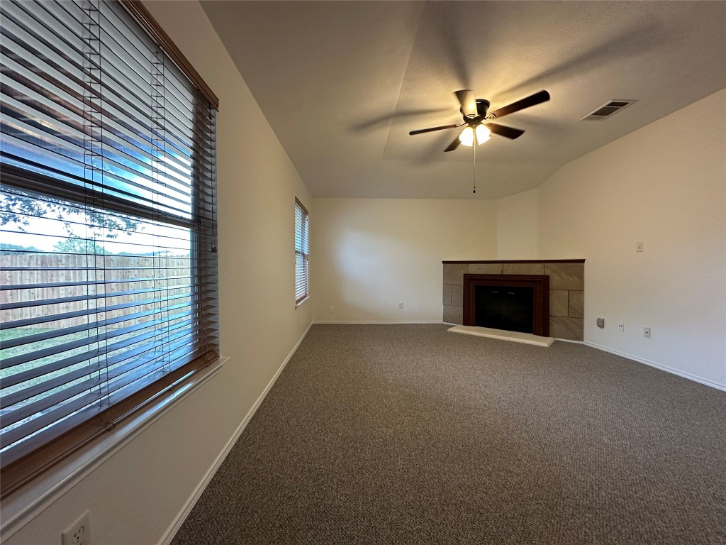 3412 Napa Valley Bend Leander, TX 78641 - Photo 11 of 27 Unfurnished living room featuring carpet floors, a tiled fireplace, ceiling fan, and vaulted ceiling