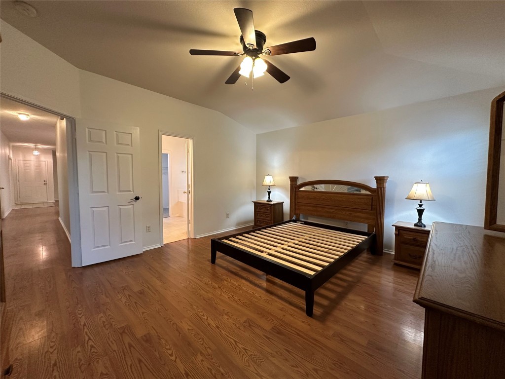 3412 Napa Valley Bend Leander, TX 78641 - Photo 20 of 27 Bedroom with dark wood-type flooring, lofted ceiling, a ceiling fan, and ensuite bath