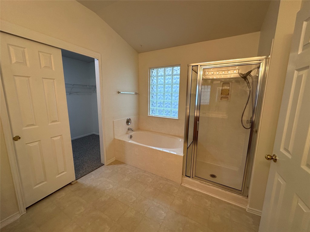 3412 Napa Valley Bend Leander, TX 78641 - Photo 24 of 27 Bathroom featuring a garden tub, a shower stall, vaulted ceiling, and a spacious closet