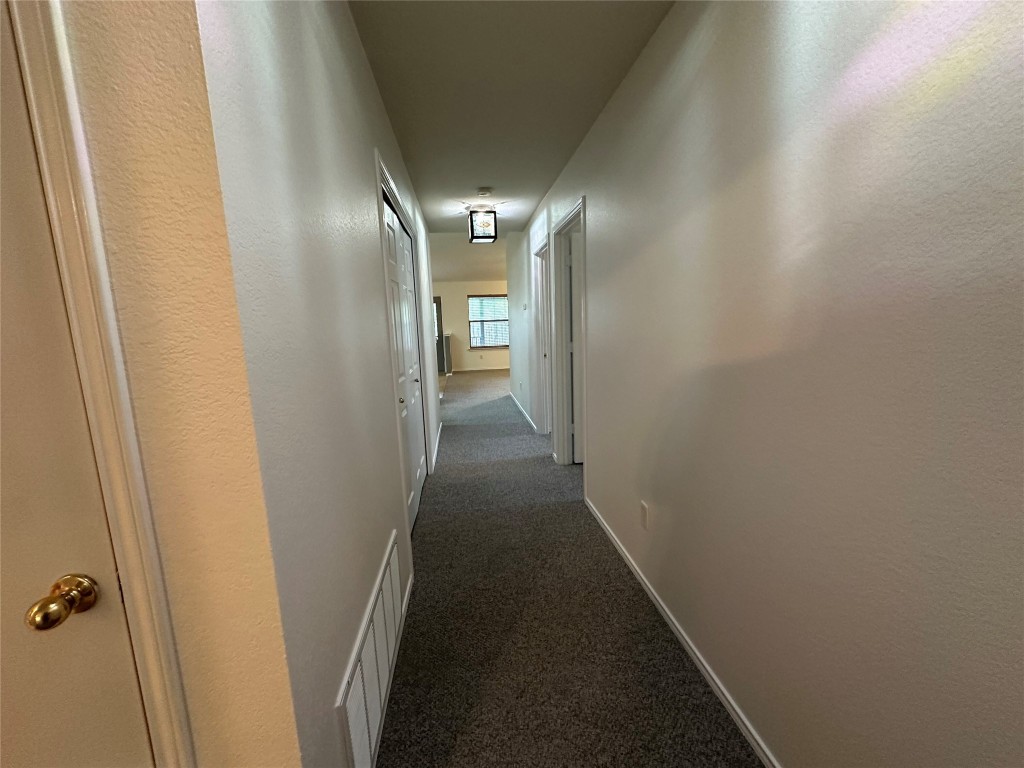 3412 Napa Valley Bend Leander, TX 78641 - Photo 7 of 27 Hallway featuring dark carpet and a textured wall