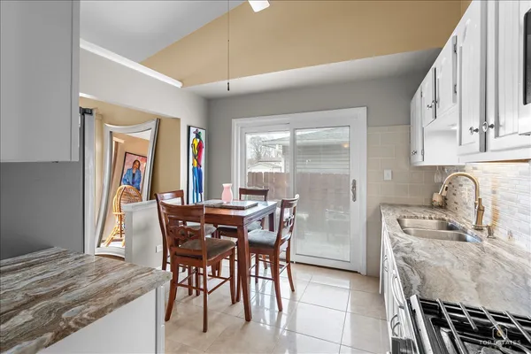 a kitchen with stainless steel appliances kitchen island granite countertop a table chairs and a refrigerator