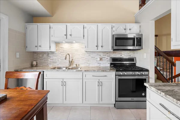 a kitchen with a table chairs a refrigerator and a stove top oven