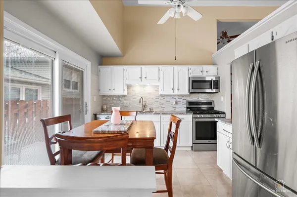 a kitchen with granite countertop a stove a sink a dining table and chairs