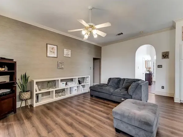 an empty room with wooden floor fan and windows