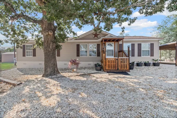 a front view of a house with a yard and tree