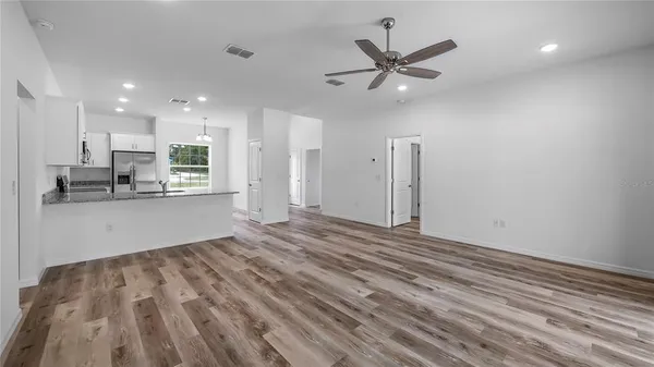 a view of an empty room with kitchen appliances and a ceiling fan