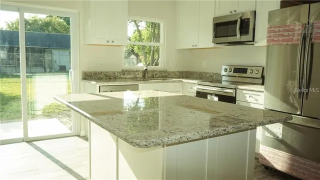 a kitchen with kitchen island granite countertop a sink a counter top space appliances and cabinets