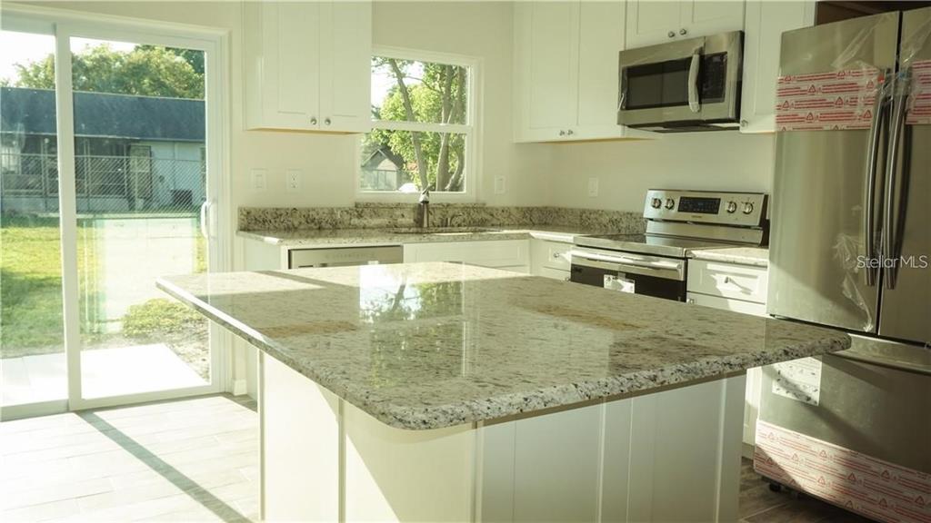3409 Vidal Street New Port Richey, FL 34655 - Photo 3 of 8 a kitchen with kitchen island granite countertop a sink a counter top space appliances and cabinets