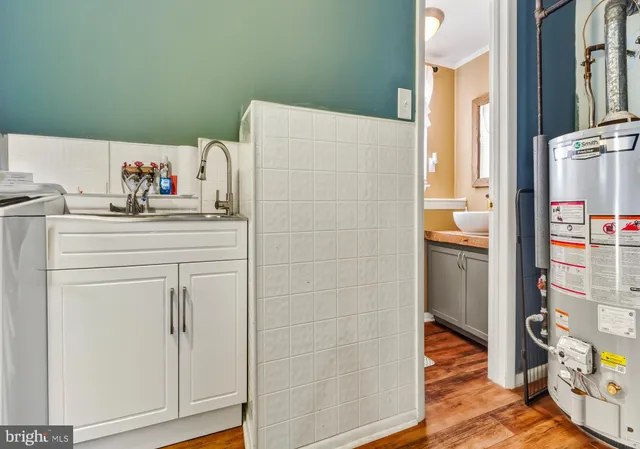 a utility room with fridge and wooden floor